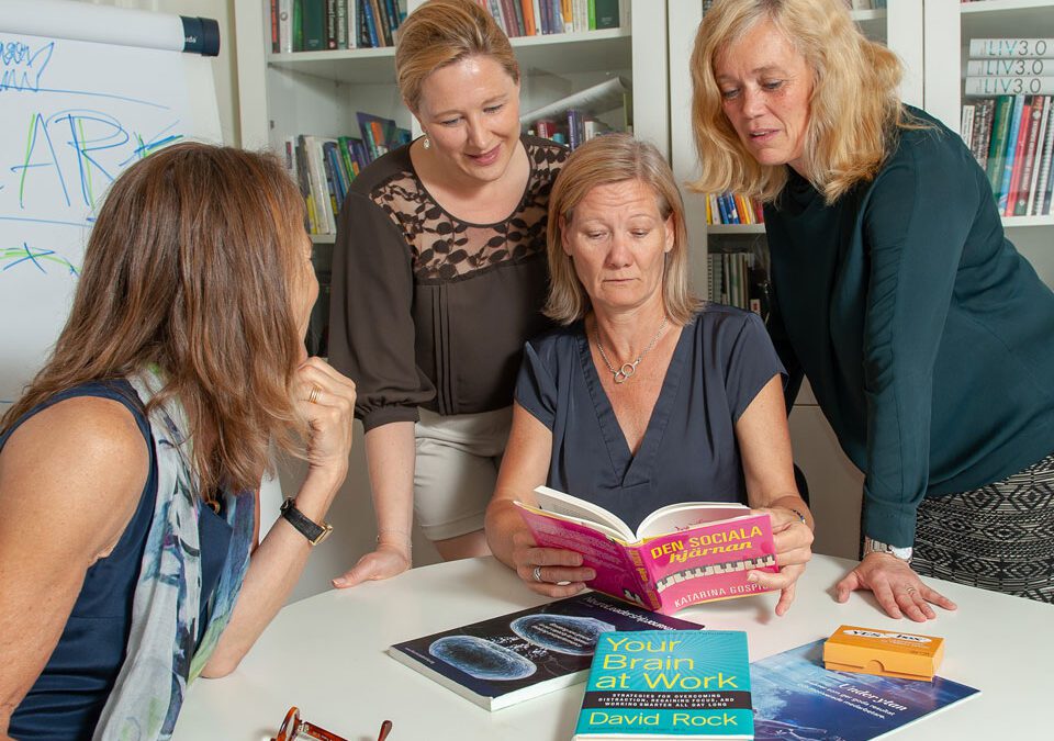 Kicki molin, Carina Vinberg, Lotta Strindberg och Agneta Lundgren runt ett bord och läser ur boken "den sociala hjärnan"